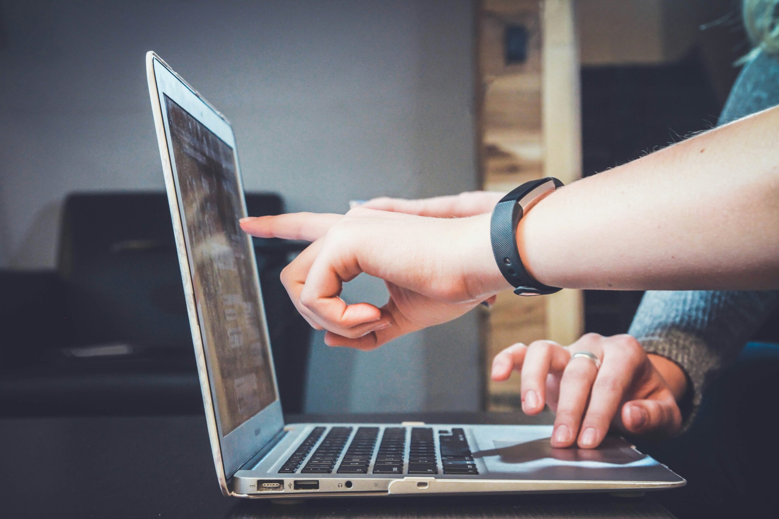 a hand pointing at something on a laptop screen